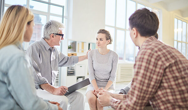 Man giving a presentation to a group with hand on women's shoulder